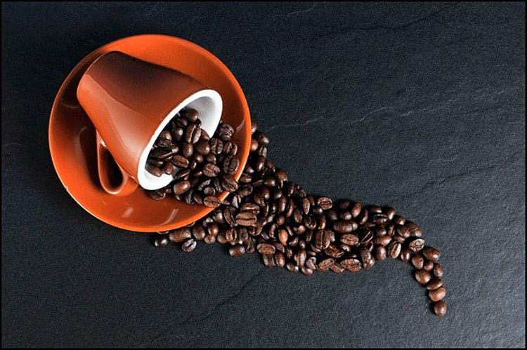 coffee beans spilling from orange cup